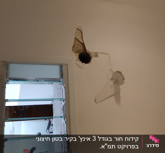 קידוח חור עגול בקיר בטון ליד חלון שלבים להעברת צנרת